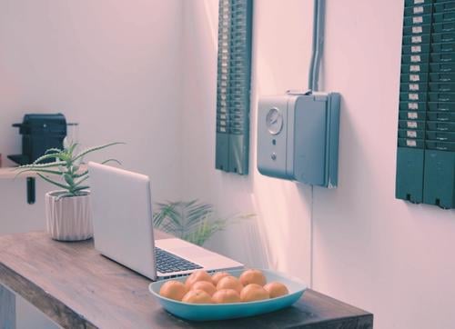 Bundi clock on wall, laptop, bowl oranges and pot  plant on desk