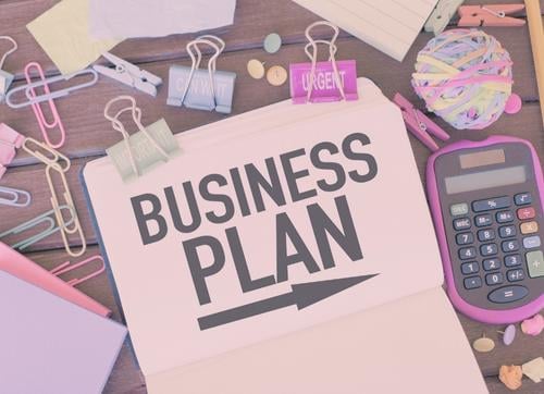 Business plan & arrow typed on a book with stationary