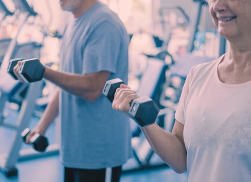 elderly man and woman lifting weights and flexing