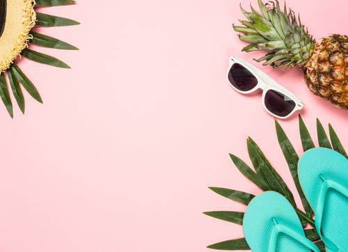 holiday palm leaves hat, thongs sunglasses and pineapple on pink background