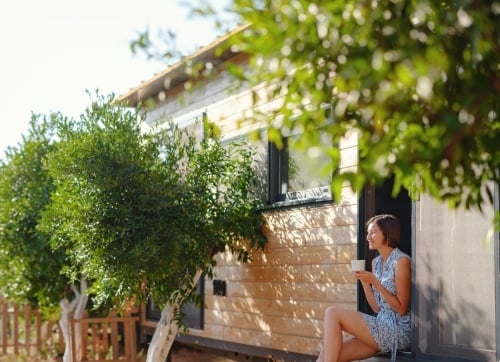 lady sitting in doorway of granny flat with trees around