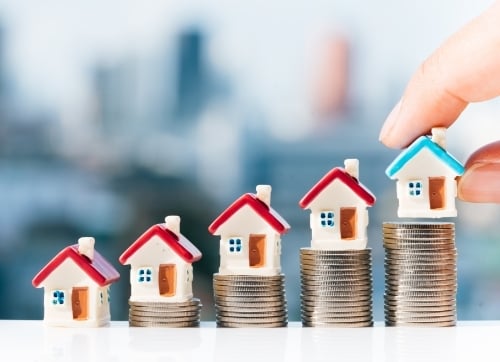 property investments - tiny houses in a row sitting on top of coins