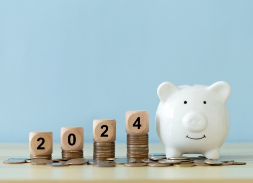 stacked coins with blocks on top saying 2024 and and white piggy bank