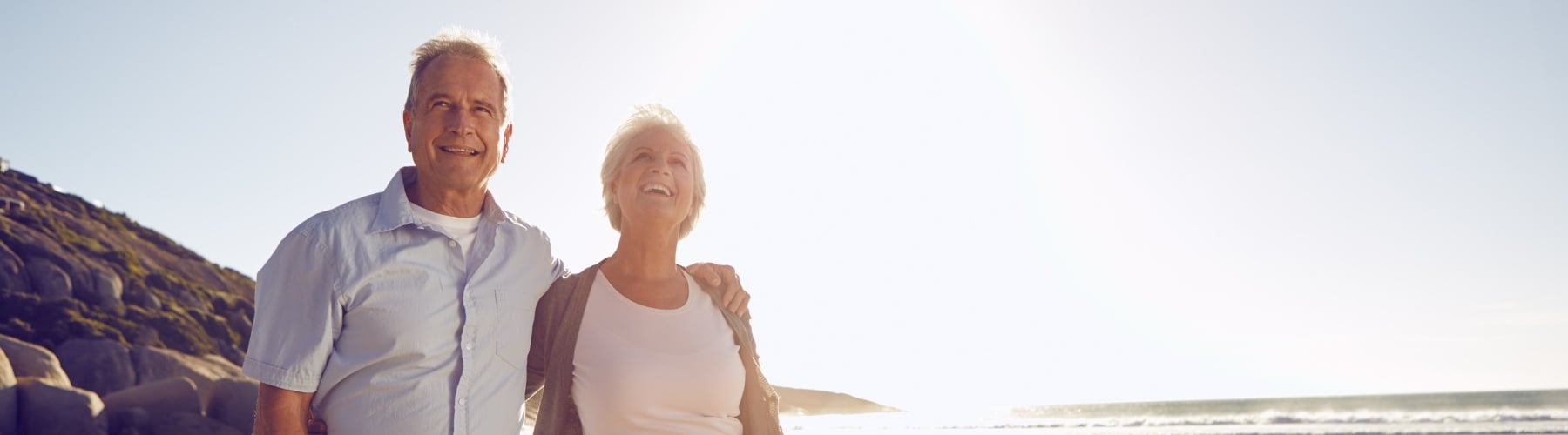 Centrelink - happy retired couple walking along the the beach