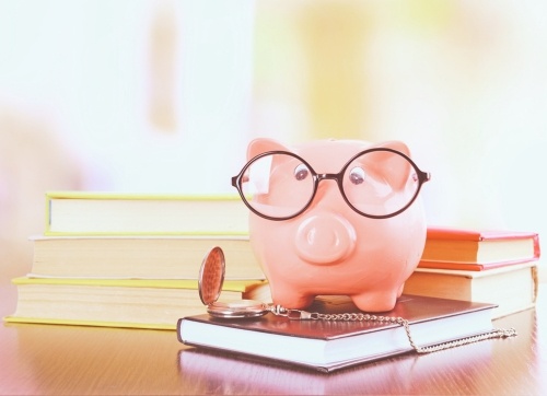 Countdown to Retirement - pink piggybank with glasses on books with a stop watch