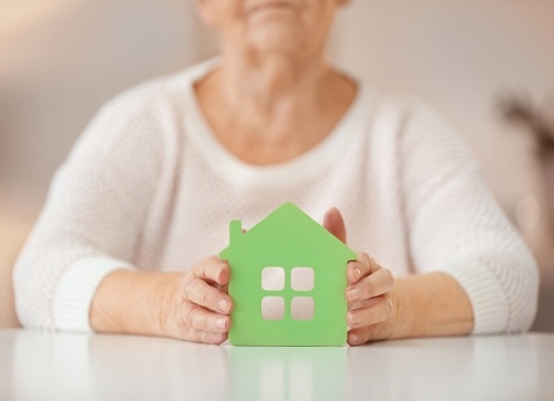 Elderly woman holding a cardboard cutout green house