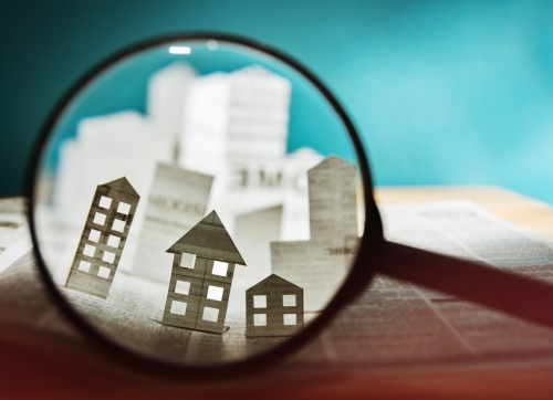 Paper houses and building in a magnifying glass