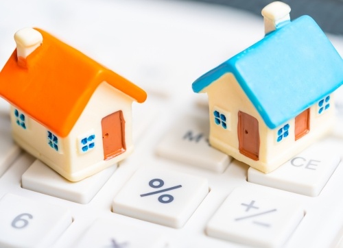 two miniature toy houses on a keypad with a percentage symbol