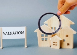 valuation sign and magnifying glass on timber house blocks