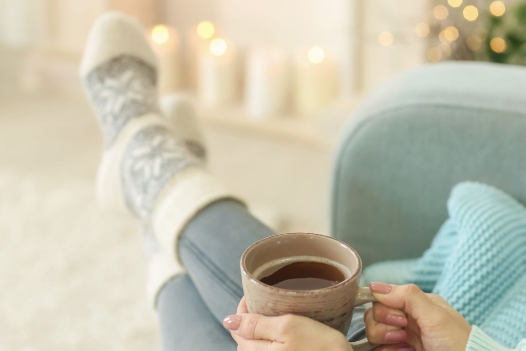 Woman sitting with her legs stretched out and crossed, relaxing with a cup of tea